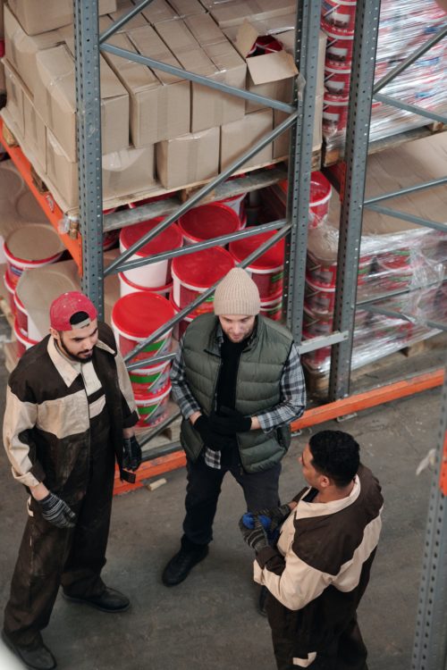 3 men standing in a warehouse talking